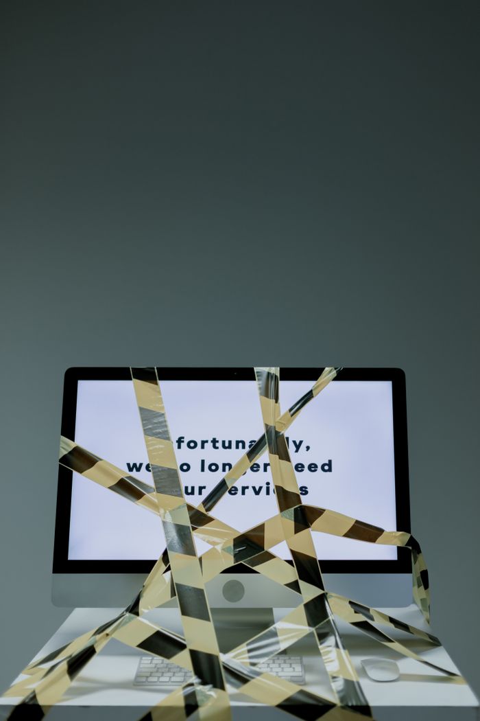 creative-01 A computer monitor showing a dismissal notice with security tape, representing the loss of a job.