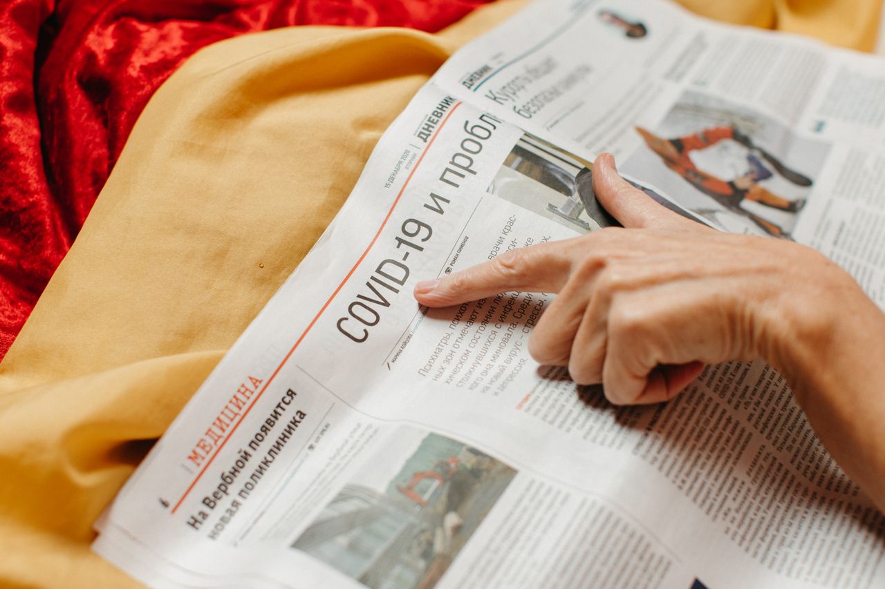 brand-01 A close-up shot of a hand pointing at a COVID-19 headline in a newspaper.